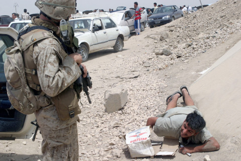 An Iraqi Security Force (ISF) Commando with US Marine Corps guards a civilian as his vehicle, and others, is searched near Ar Ramadi.